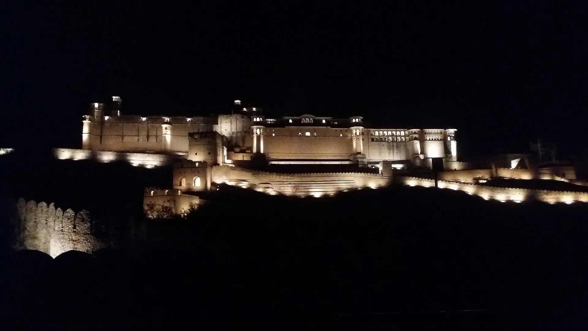 A heritage fort palace illuminated against the evening sky