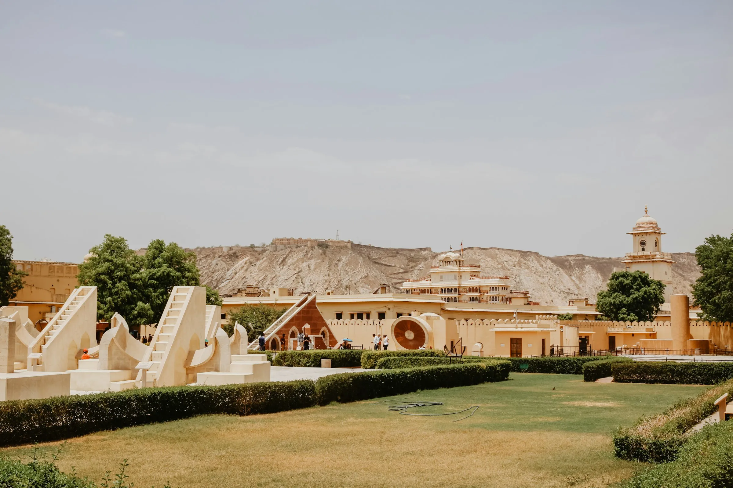 The masonry astronomical instruments of the Jantar Mantar observatory in Jaipur, set against the surrounding hills