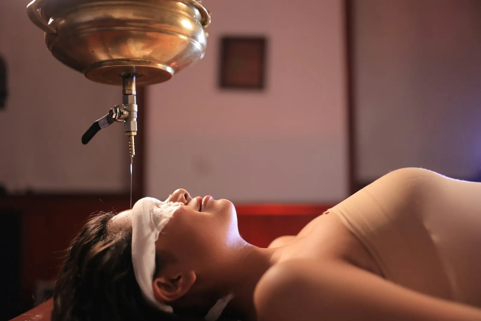 A woman receiving a traditional shirodhara oil treatment on her forehead at an Ayurveda centre in Uttarakhand