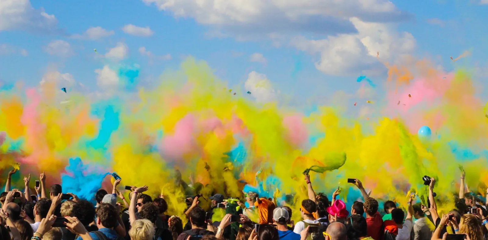 A crowd doused in clouds of pink and yellow coloured powder during a Holi celebration in India