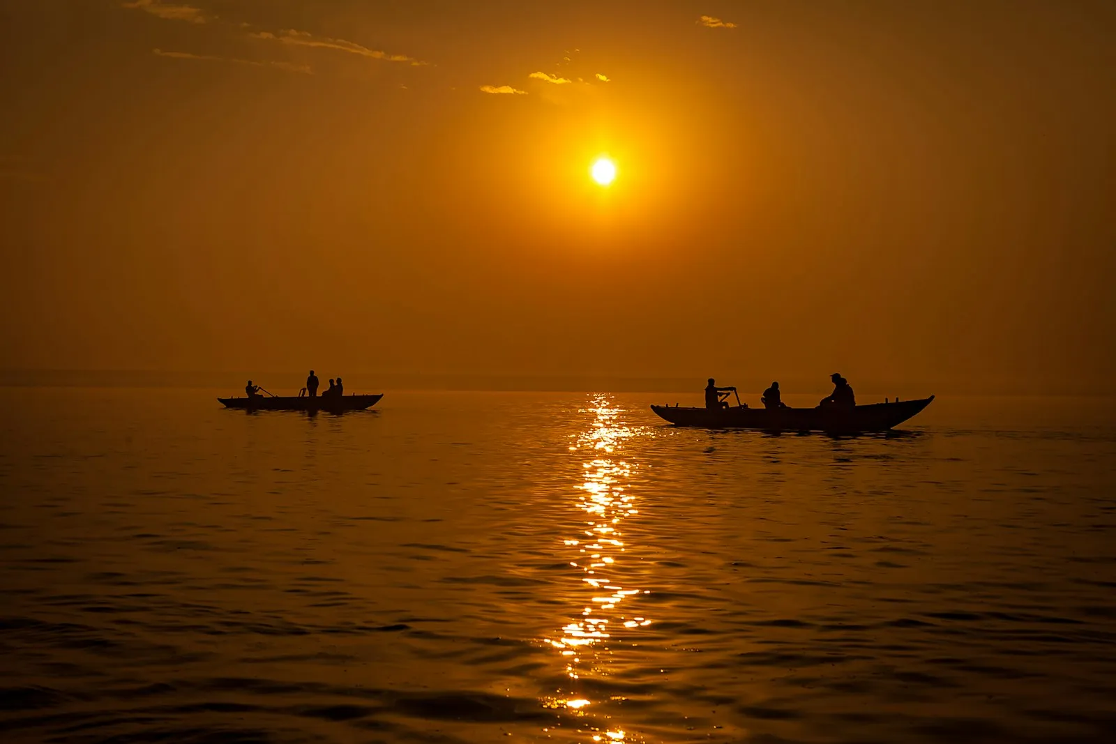 Silhouetted pilgrims in a boat on the Ganges at golden hour in Varanasi