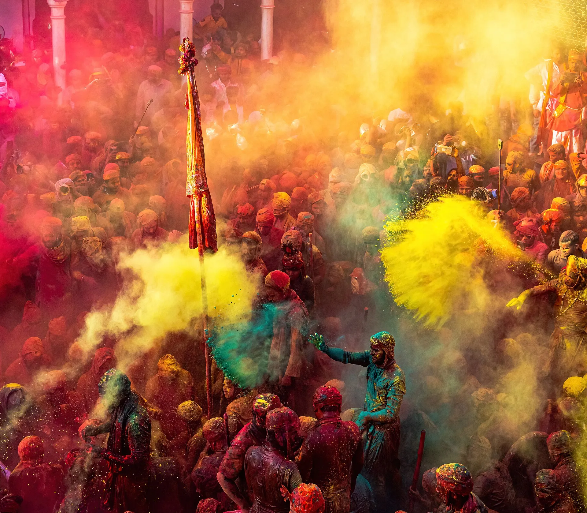 Revellers covered in clouds of pink and yellow powder during Holi celebrations