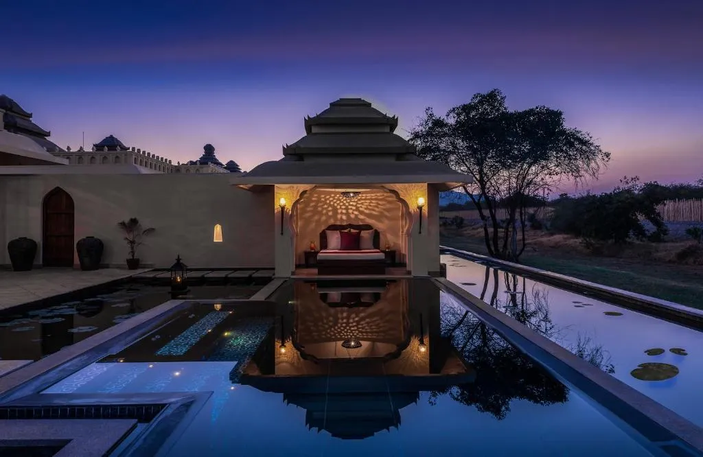 Private pool pavilion lit at dusk beneath a violet sky